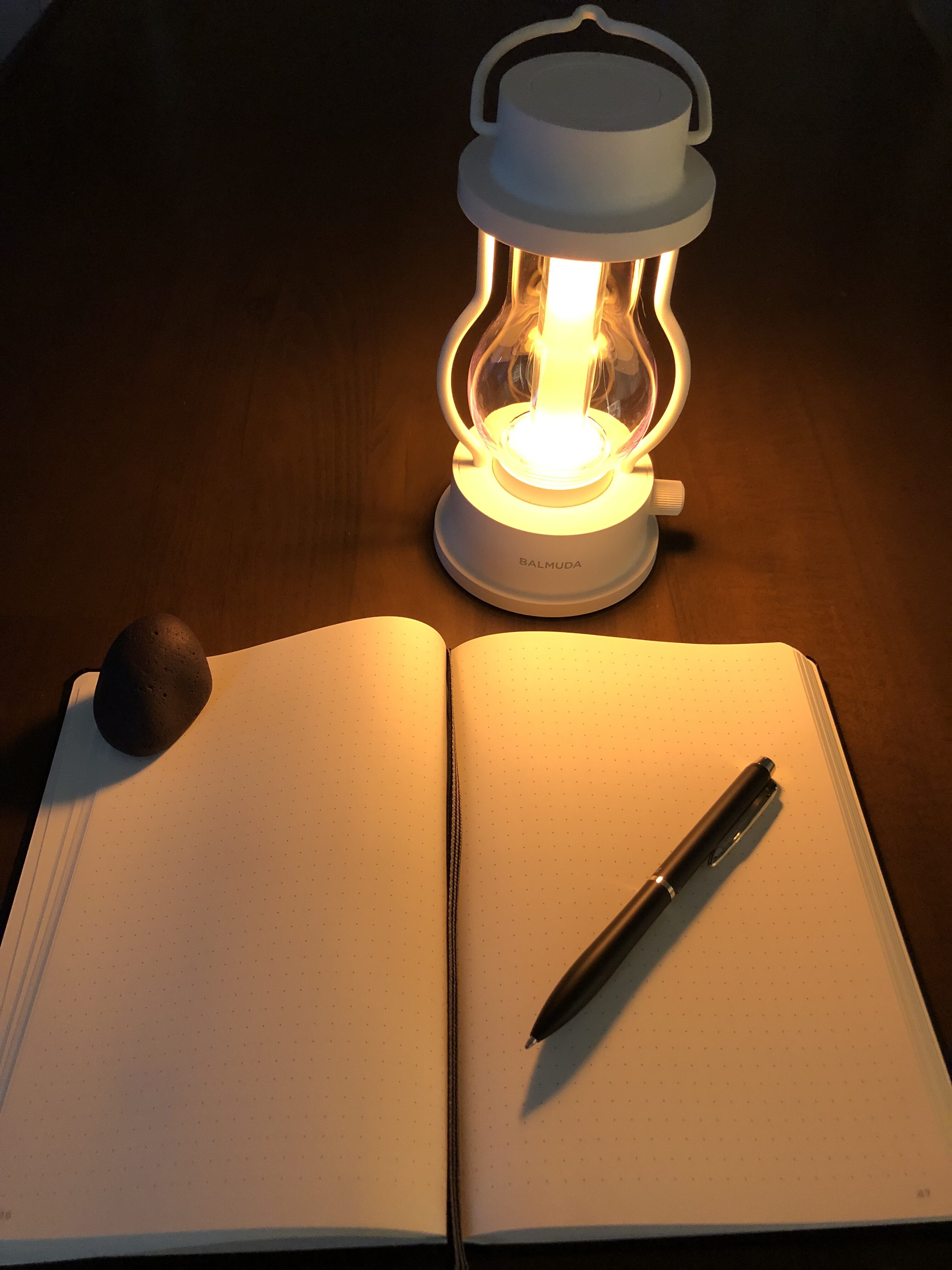 Journal, pen, lamp, and stone arranged for daily journaling and reflection practice.