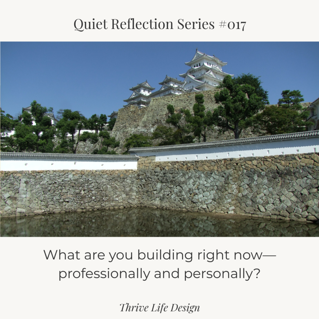 White castle with a surrounding moat, reflected in calm water.