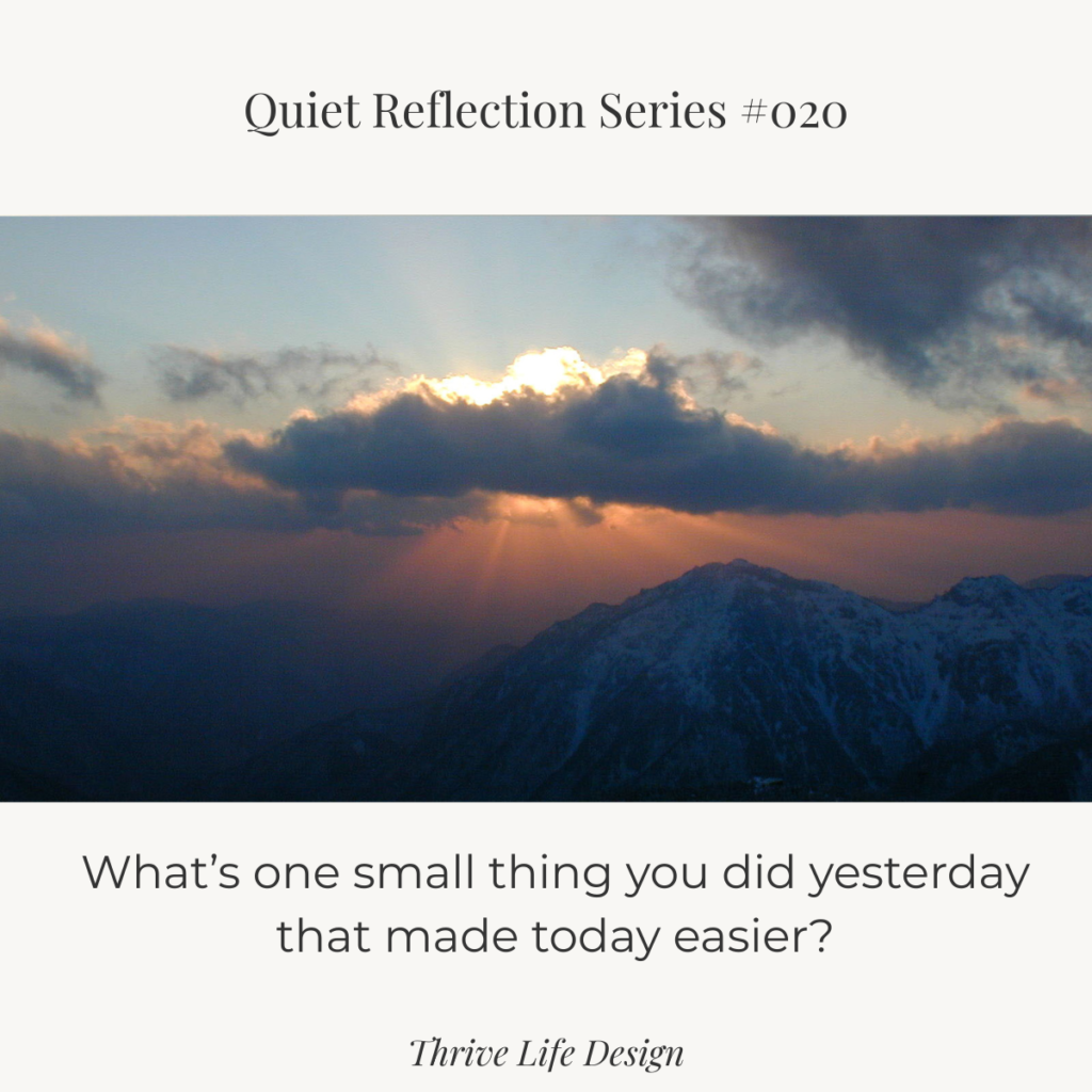 Soft sunrise over distant mountains, with layered clouds in gray-blue tones and a warm orange glow near the horizon.