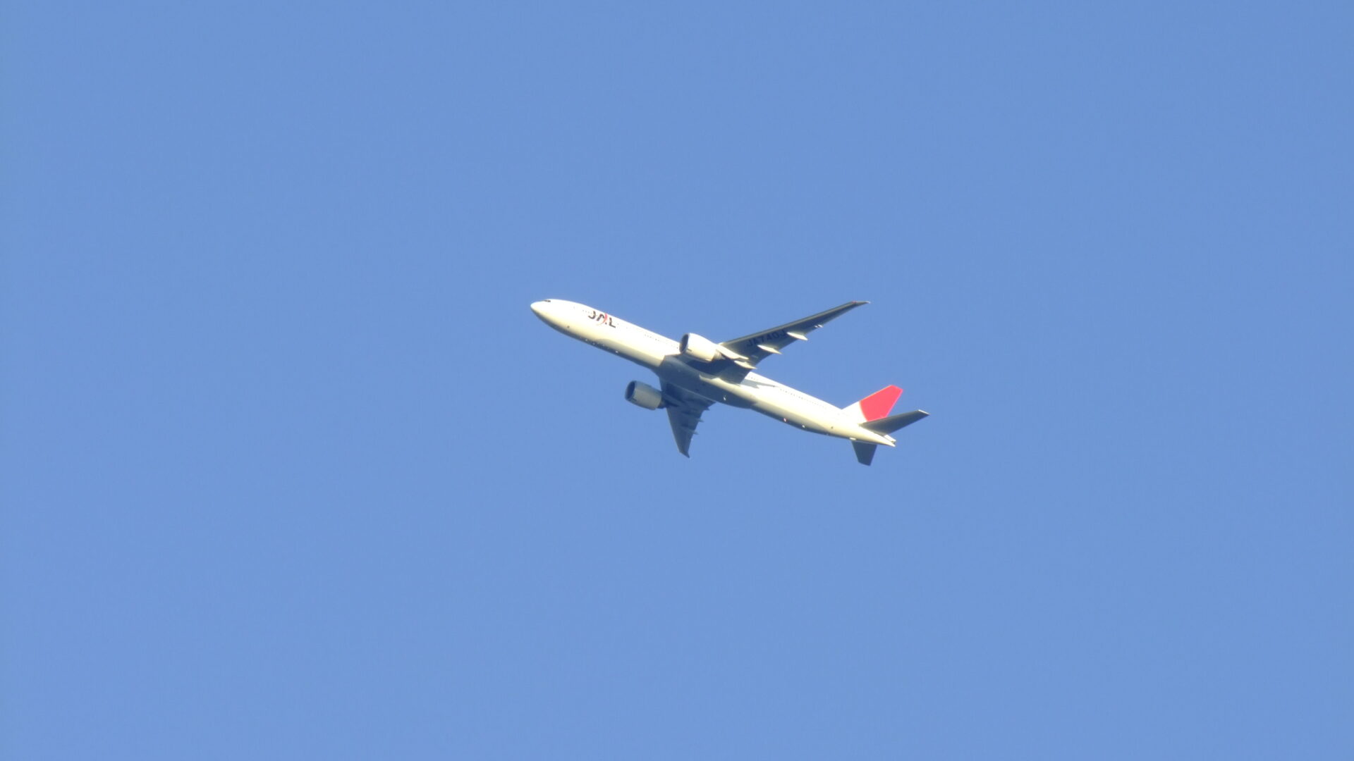 A Japan Airlines airplane flying across the sky.